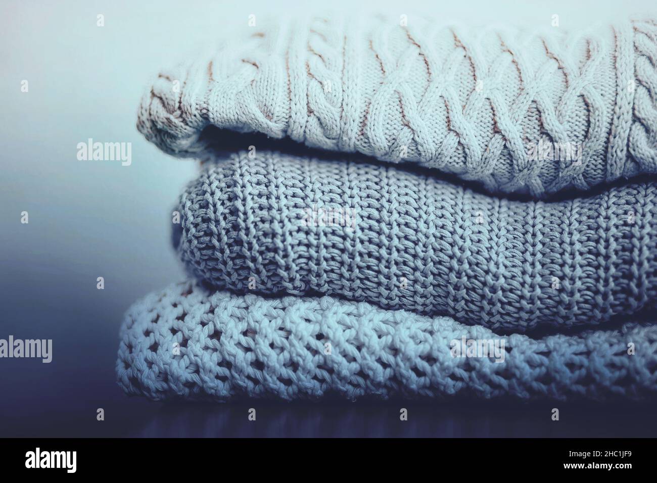 Three woolen warm sweaters with patterns are stacked in a pile