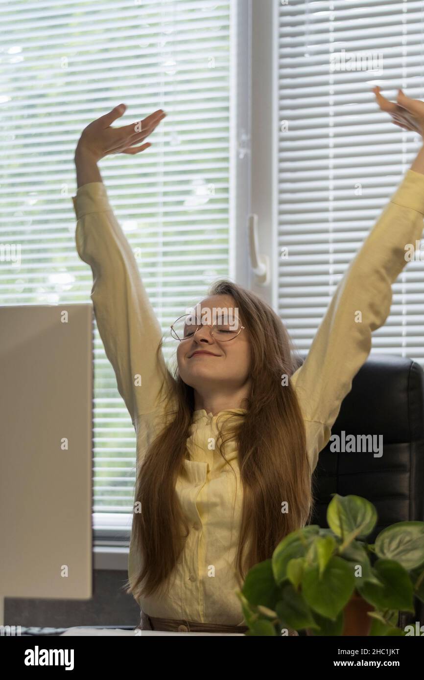 The girl happily raised her hands up and stretches while sitting at the ...