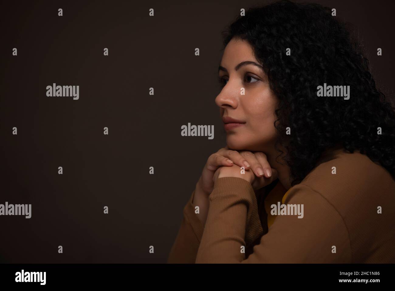 Portrait of an adult woman looking away with her chin resting on both
