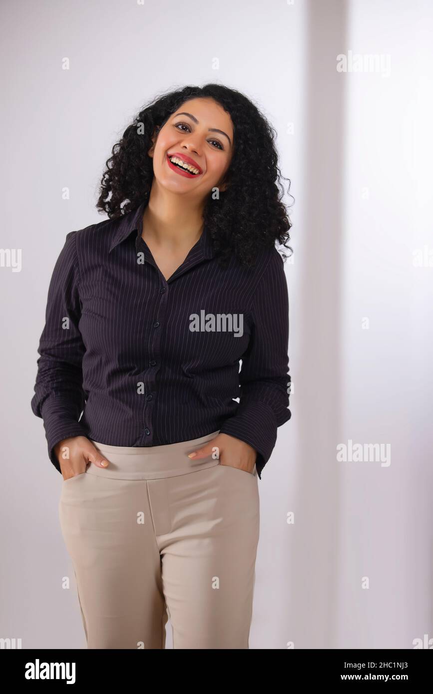 Adult woman in formal clothing smiling with both hands on pockets Stock Photo
