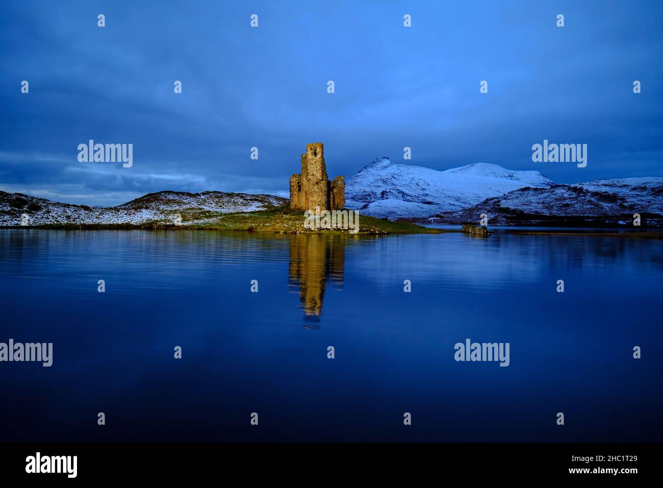 The 16th century Ardvreck Castle on Loch Assynt in Sutherland, Scotland, artificially lit after sunset. Stock Photo
