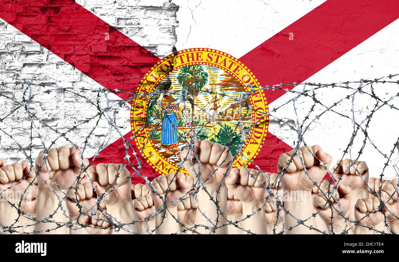 Barbed wire against the background of the inflicted flag of State of Florida and raised fists Stock Photo