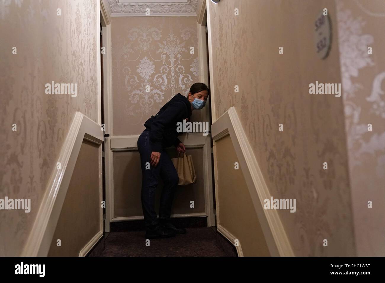 A volunteer delivers breakfast to a homeless person in their room at a
