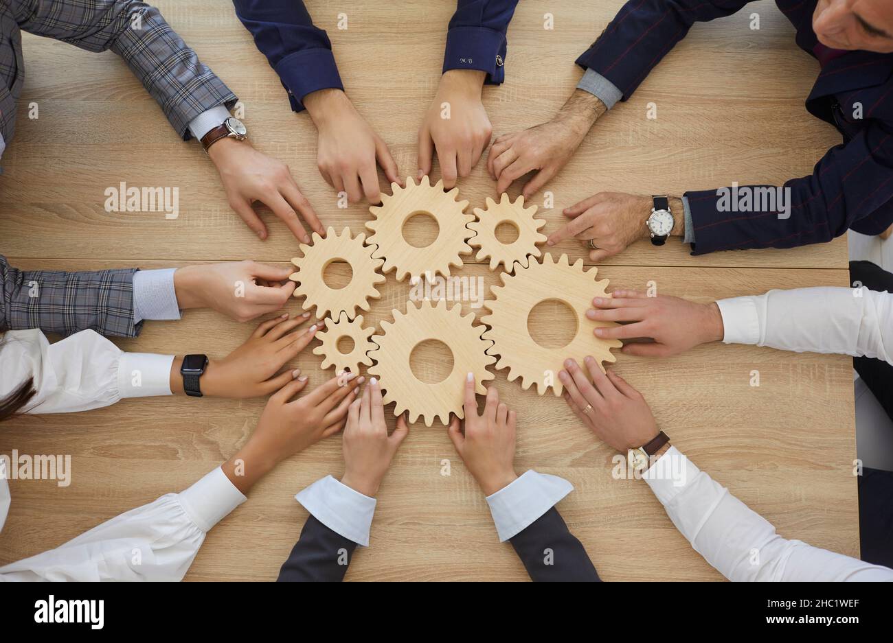 Business people stacking wooden gears next to each other which
