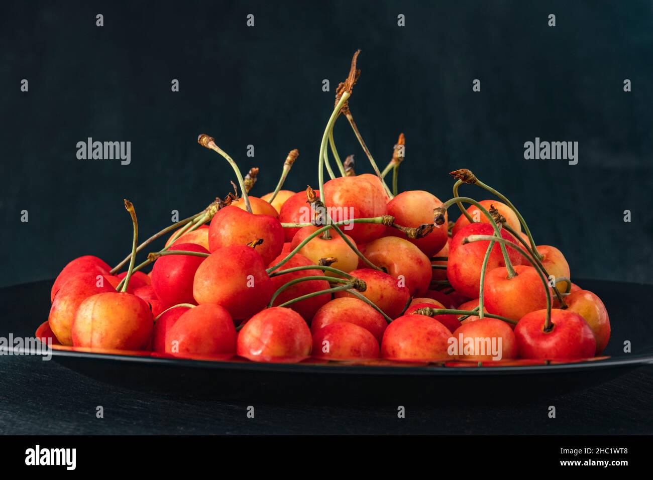 Pink cherries on platter on black background side view. Ripe juicy ...
