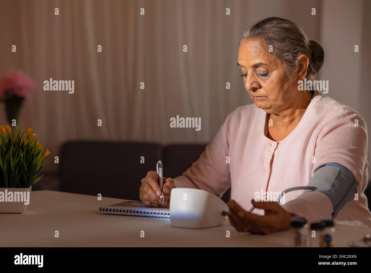 Old woman writing down her blood pressure result Stock Photo