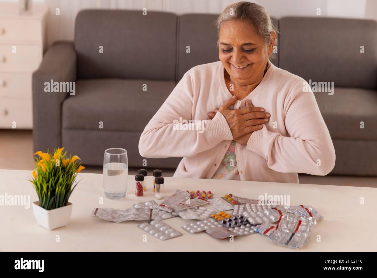 Old woman going to take medicine kept on centre table Stock Photo