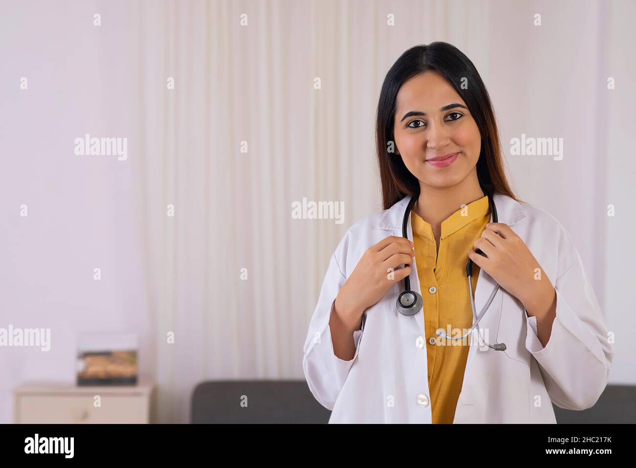 Close-up of a smiling lady doctor holding stethoscope Stock Photo