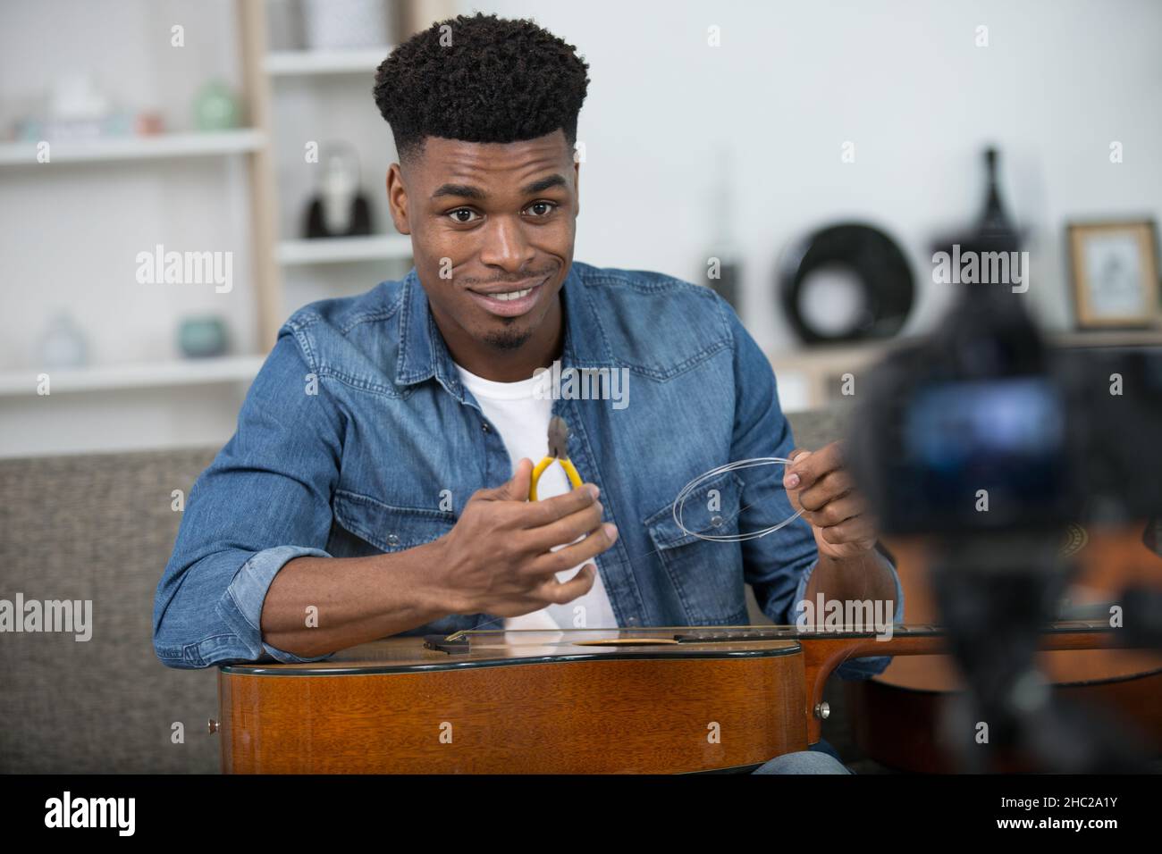 man filming a tutorial on how to restring a guitar Stock Photo