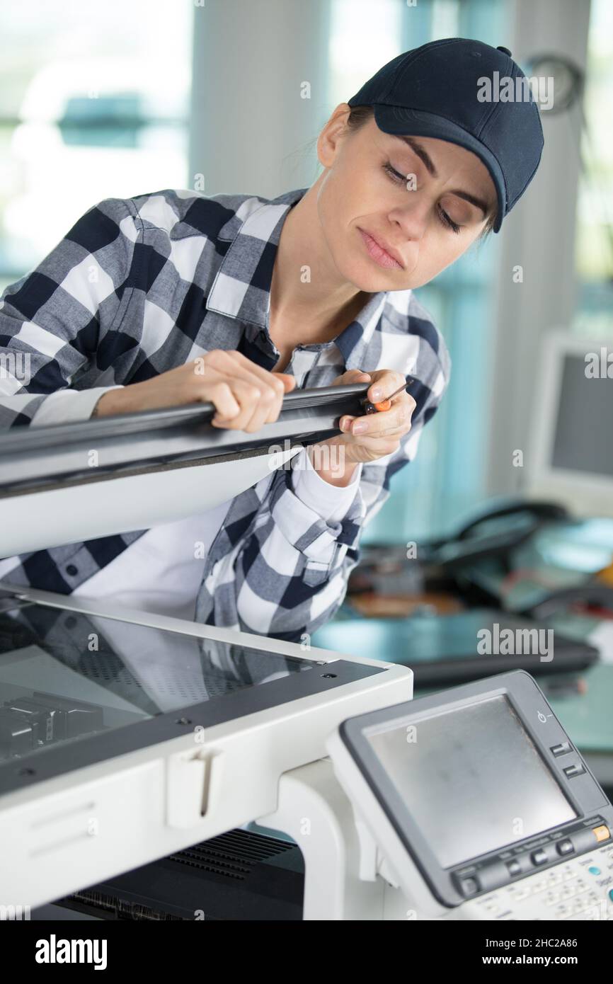 female technician using a screwdriver for fixing printer Stock Photo