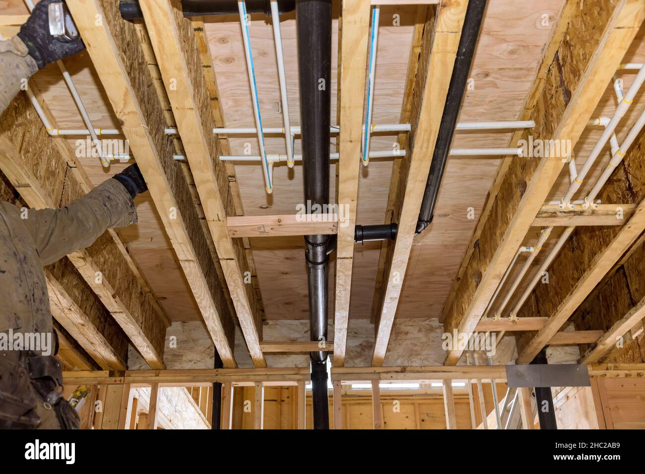 Plumber gluing sewage drain PVC pipes on the home under construction