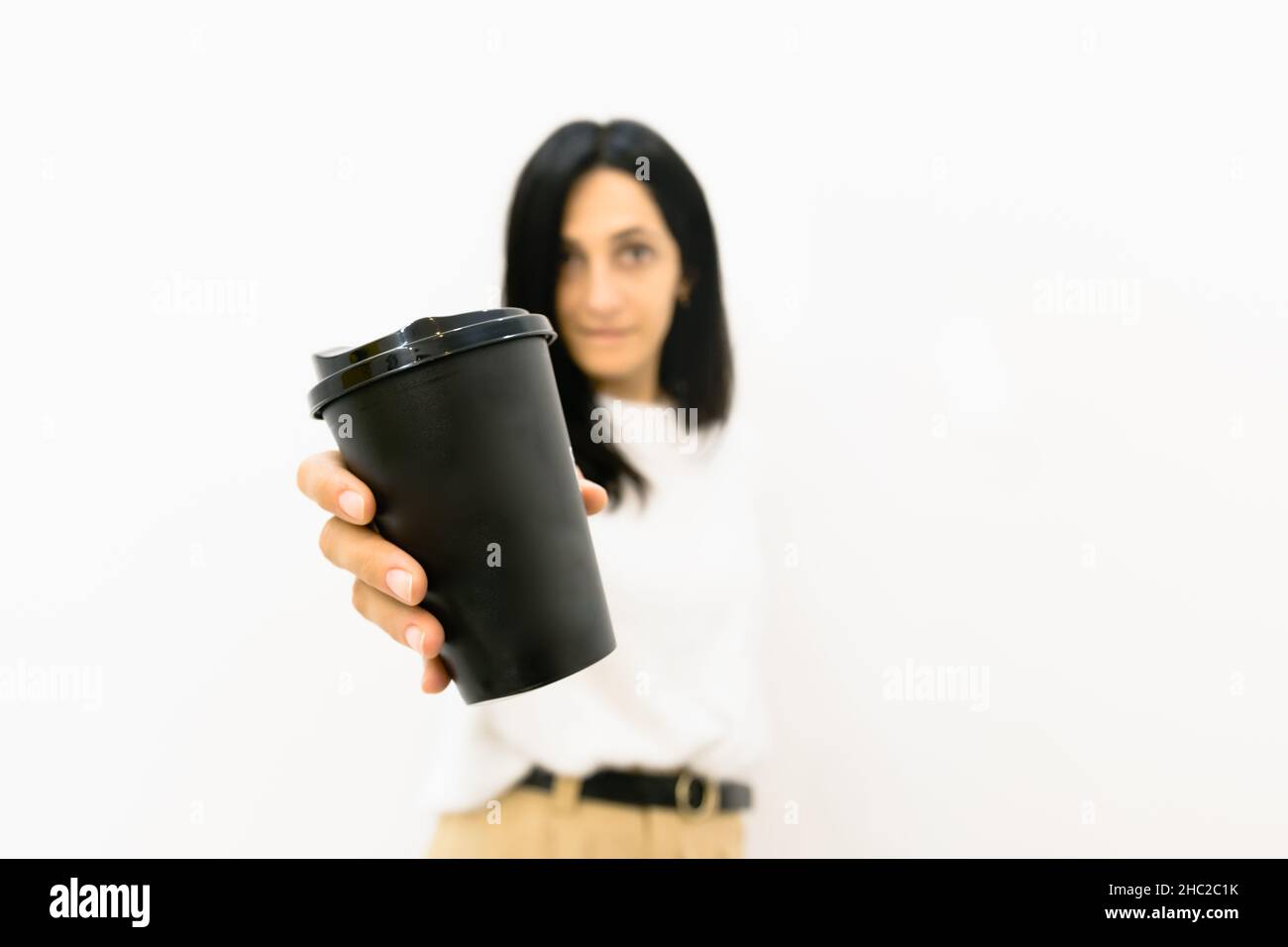 Woman in the background holds black disposable coffee paper cup with ...
