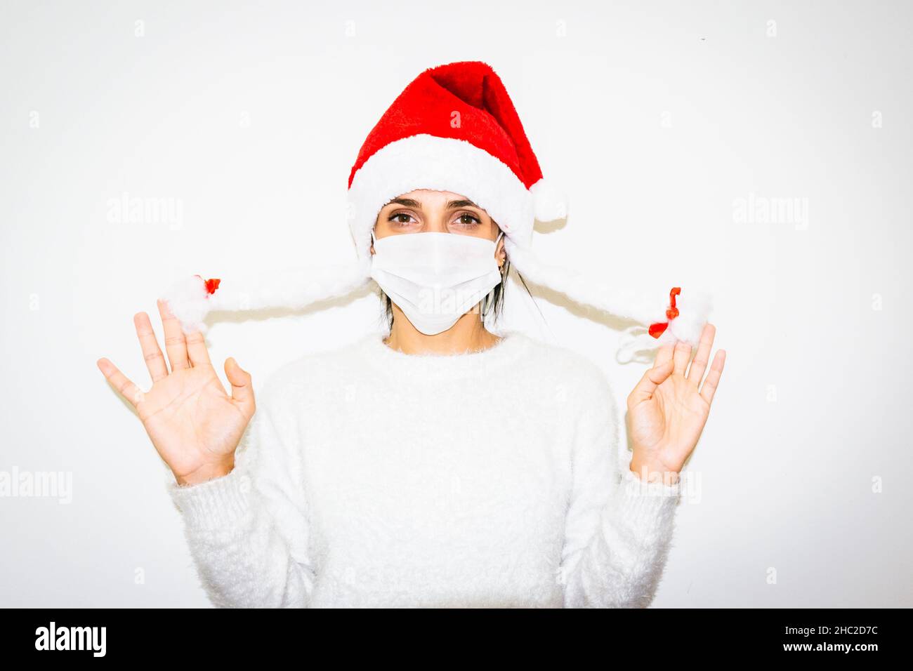 Young caucasian woman isolated in white background shows holding her white fake braids. Snowflake and Santa Claus concept. Stock Photo