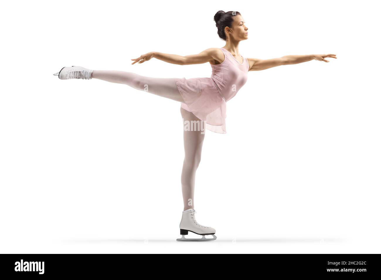 Full length shot of a young woman in a pink dress ice skating with one leg up isolated on white background Stock Photo
