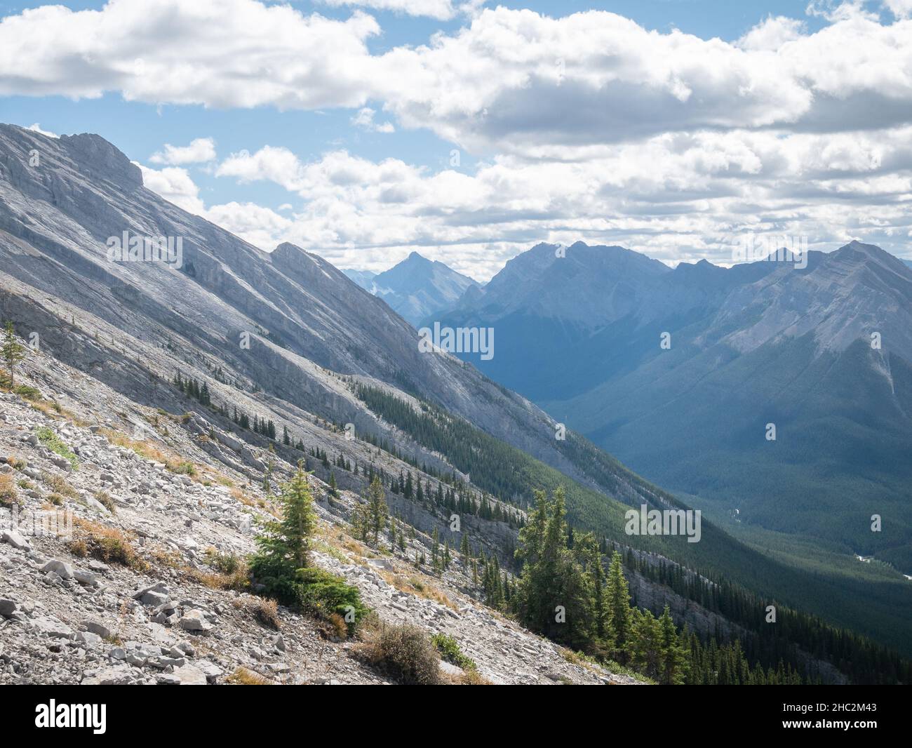 Steep slope on the way up to the mountain summit with green valley in background Stock Photo