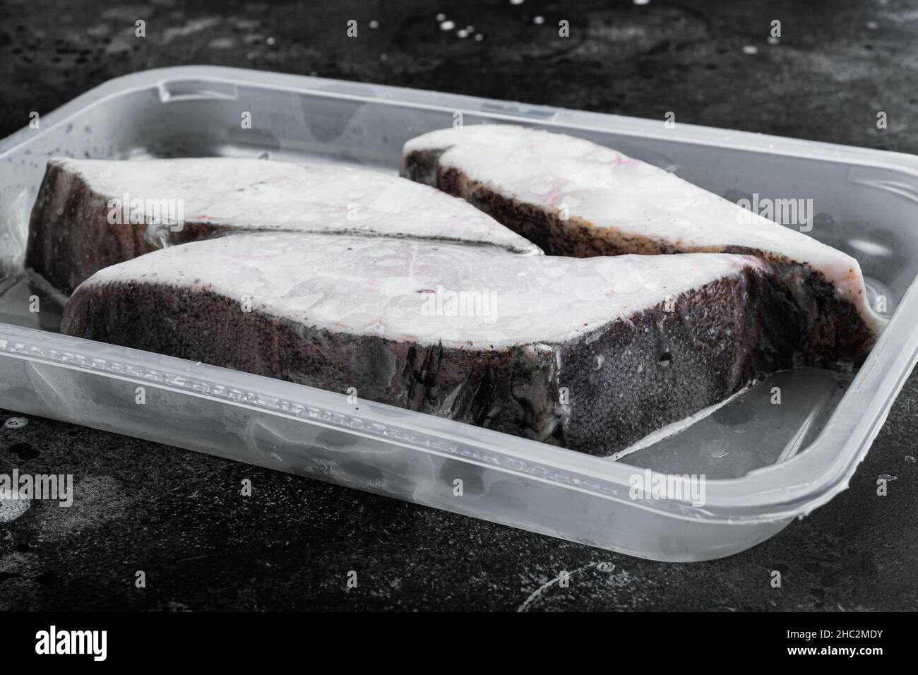 Raw fillets frozen halibut airtight vacuum pack set, on black dark