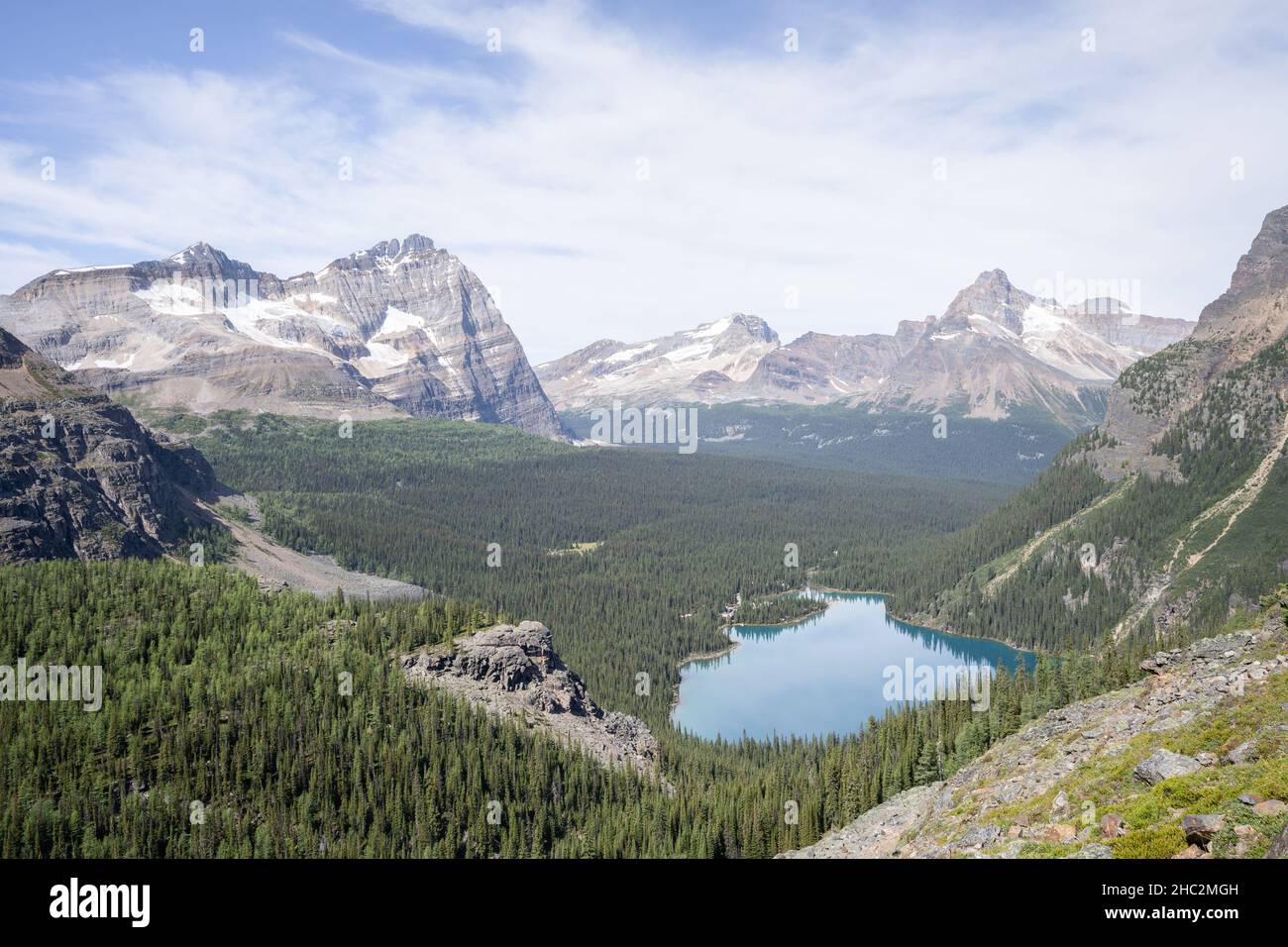 Beautiful alpine valley with blue glacier lake, forest and surrounding peaks, Canada Stock Photo