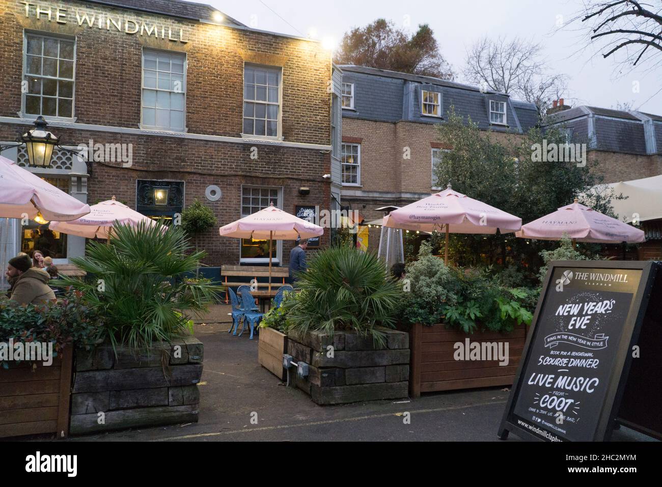London, UK, 23 December 2021: The Windmill pub on Clapham Common has a blackboard with one side advertising Christmas specials and the other side their New Year's Eve party. The hospitality sector has been hit by a wave of cancellations since the spread of the omicron variant began and there are fears for pub landlords, nighclubs and restaurant owners that a new lockdown may be brought in after Christmas. Anna Watson/Alamy Live News Stock Photo
