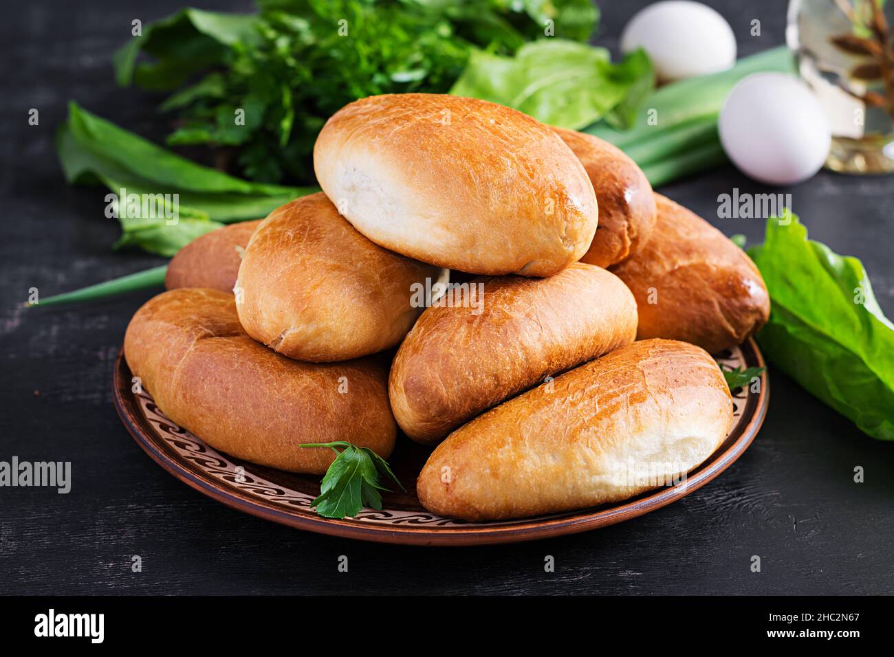 Traditional Ukrainian pies with eggs, green onion, sorrel on dark  background. Russian piroshki, homemade baked patties. Stock Photo