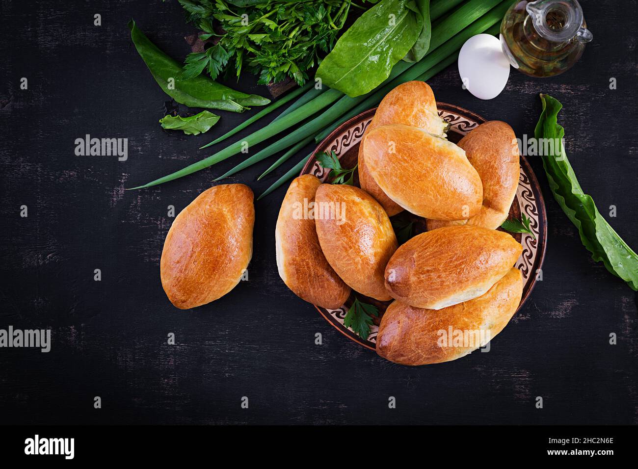 Traditional Ukrainian pies with eggs, green onion, sorrel on dark  background. Russian piroshki, homemade baked patties. Top view, above, copy space Stock Photo