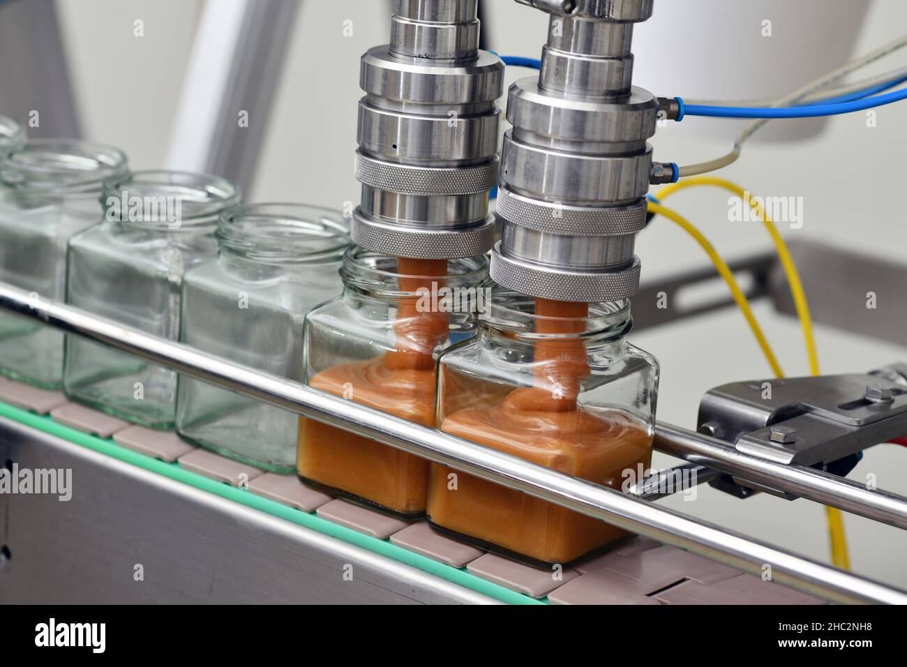 Jars of creamed honey in a packaging line at a commercial honey factory