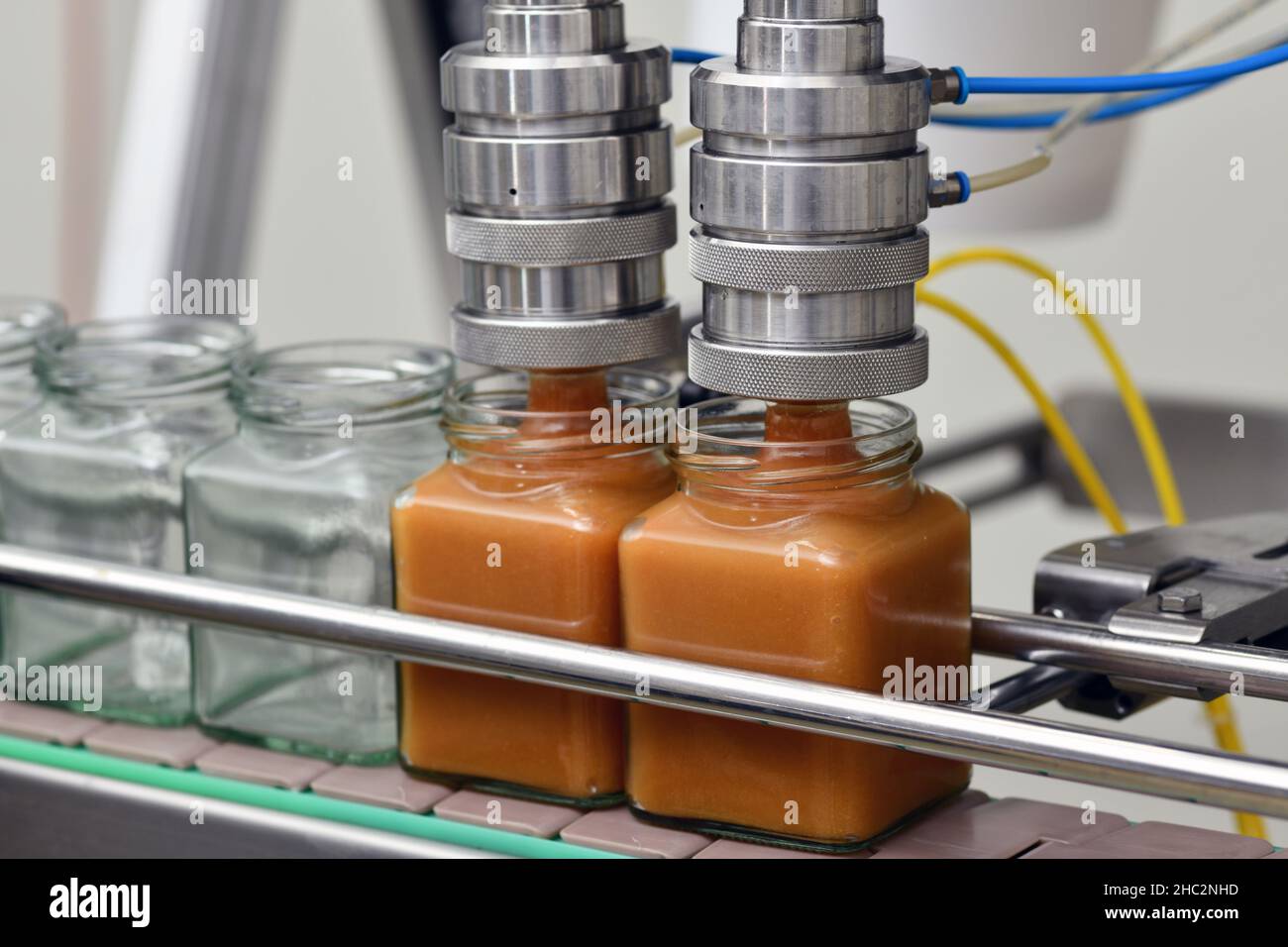Jars of creamed honey in a packaging line at a commercial honey factory