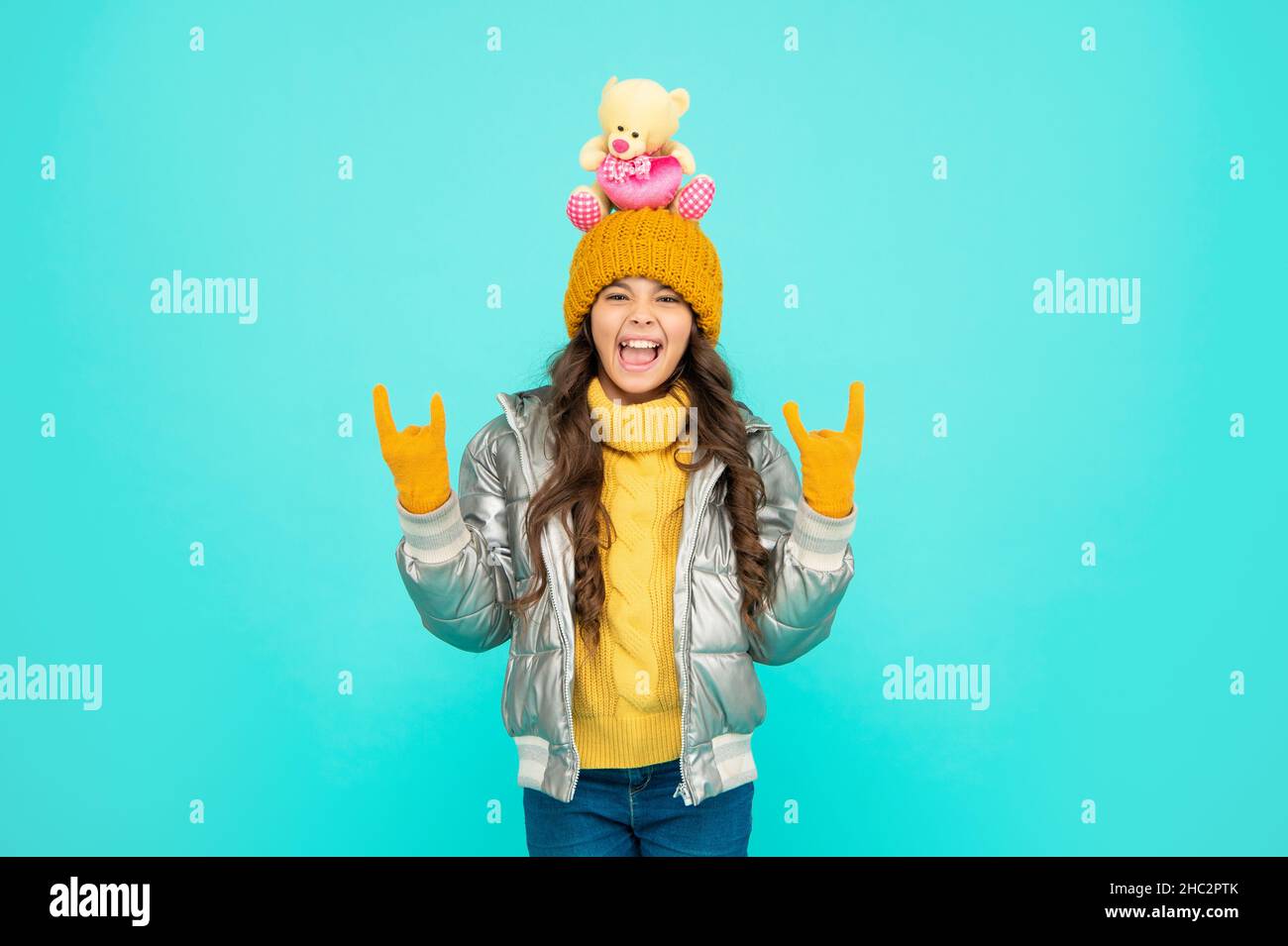childhood. teen girl hold toy bear. child wearing warm clothes on blue background. Stock Photo