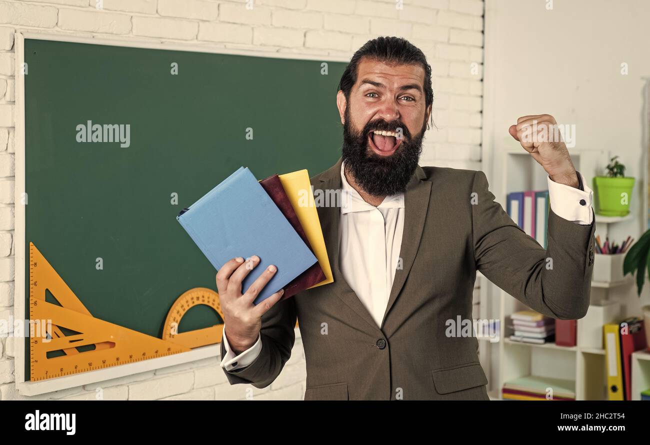 great day. learning the subject. happy man with beard holding book. literature for studying. informal education. male student in school classroom Stock Photo