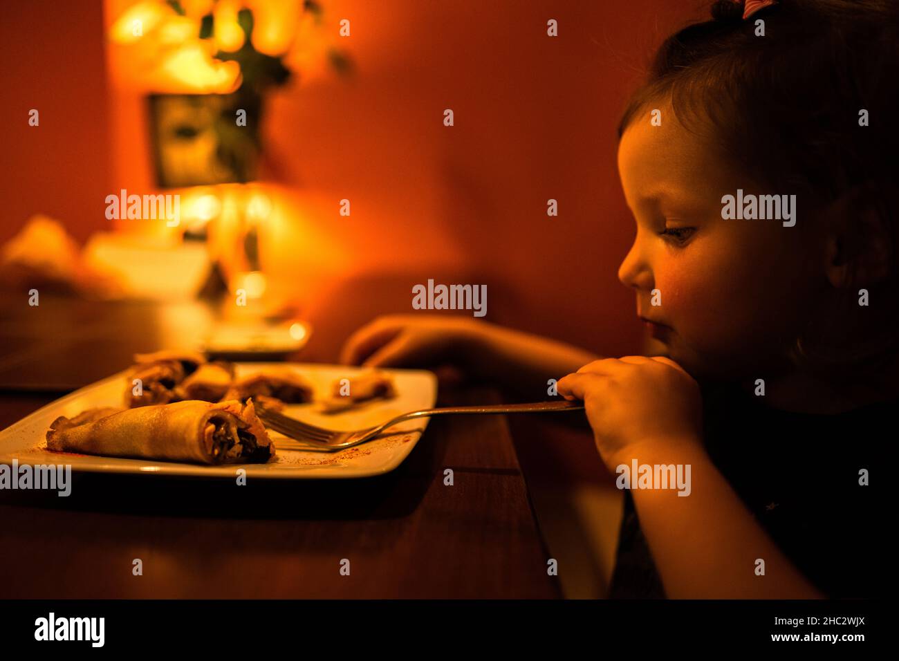 A moody shoot of a little girl eating a pancake in the restaurant. Stock Photo
