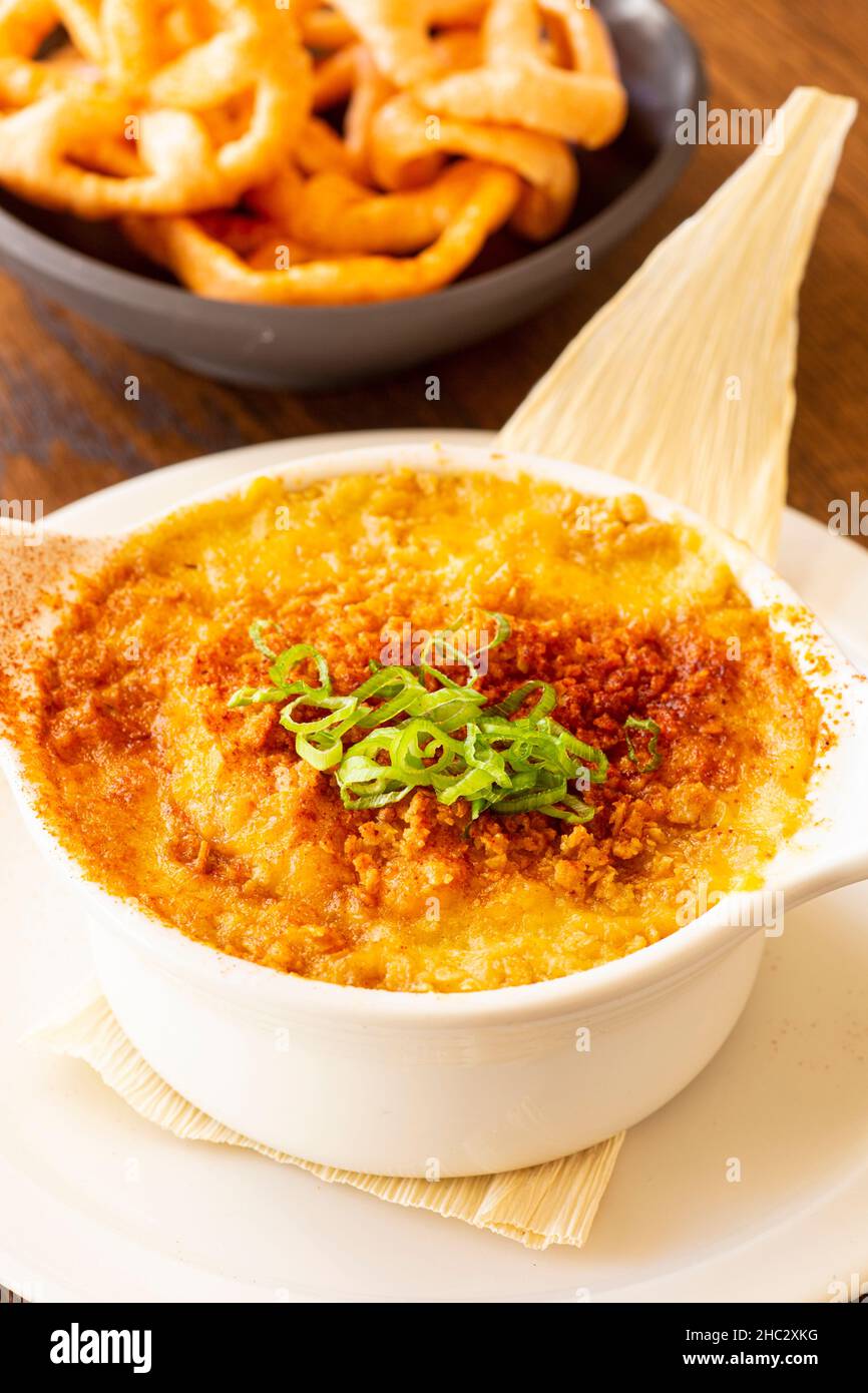 golden hominy and cheese casserole with roasted green chiles, corn tortilla and chicharrones Stock Photo