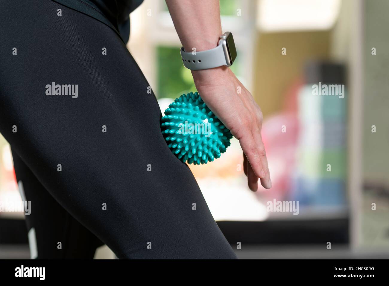 Woman using massage tool for myofascial therapy on thigh muscles