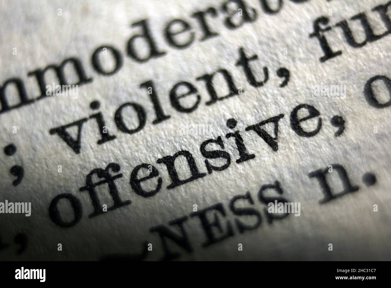 Word "offensive" and "violent" printed on dictionary page, macro close
