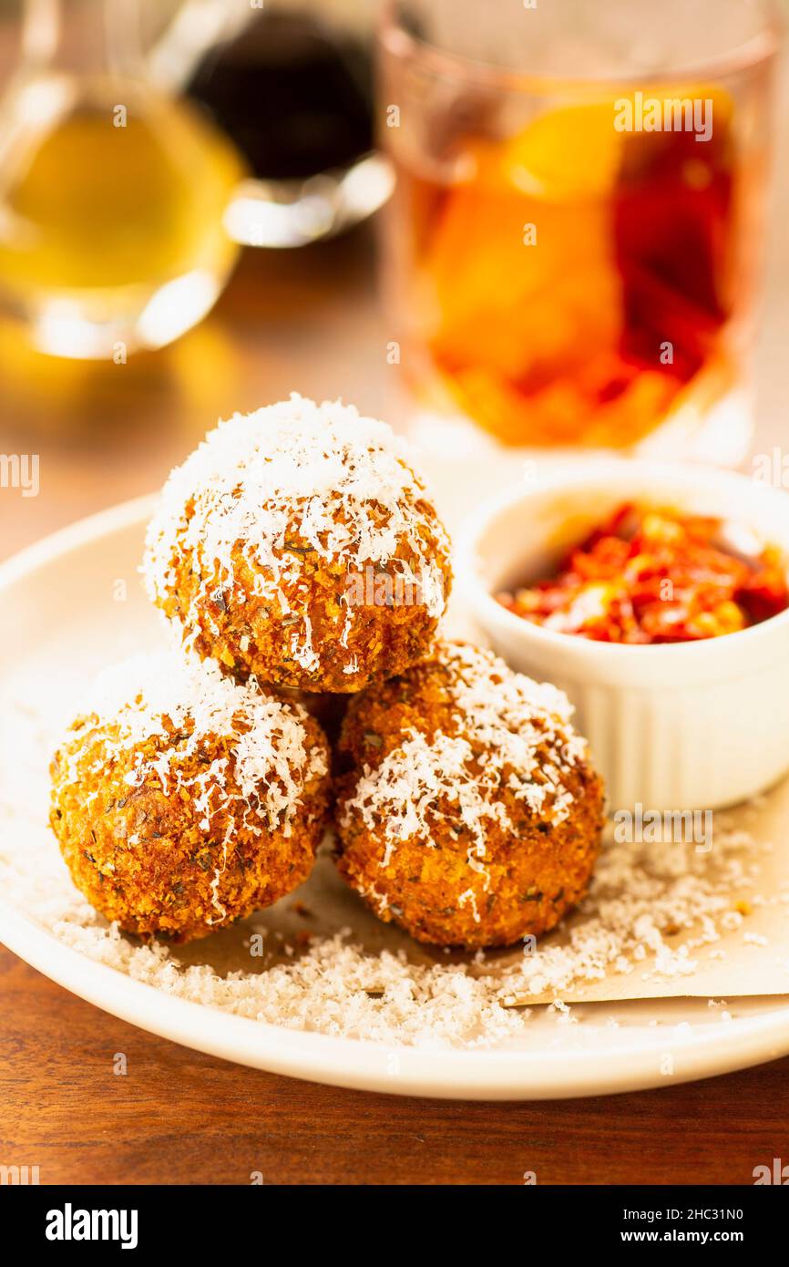 fried risotto balls and a negroni cocktail Stock Photo