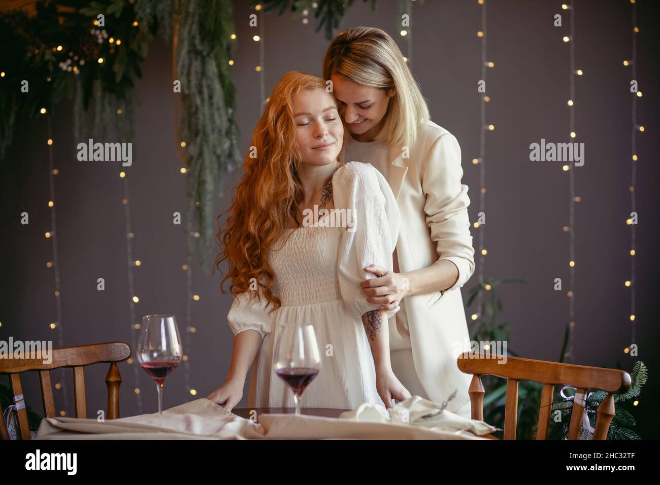 lesbian couple having dinner in a restaurant One girl hugs her beloved whispering in her ear Stock Photo