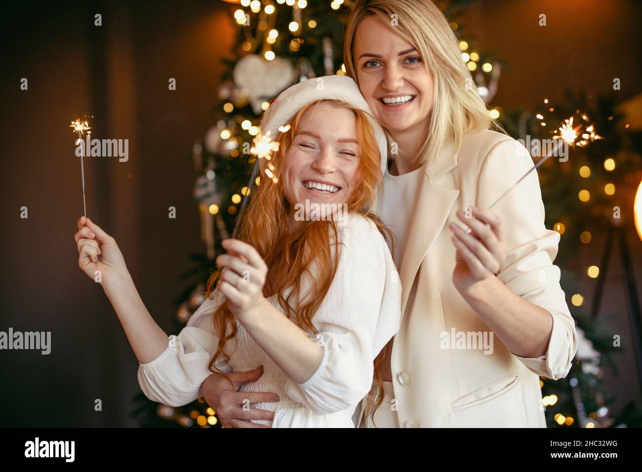 lesbian couple having dinner celebrating a holiday Girls burn sparklers and smile at the camera Stock Photo