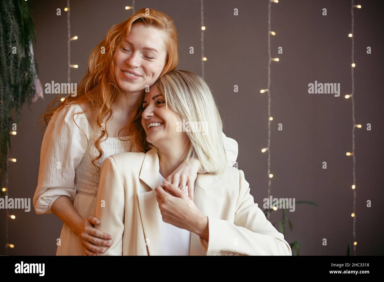 lesbian couple having dinner in a restaurant One girl hugs her beloved whispering in her ear Stock Photo