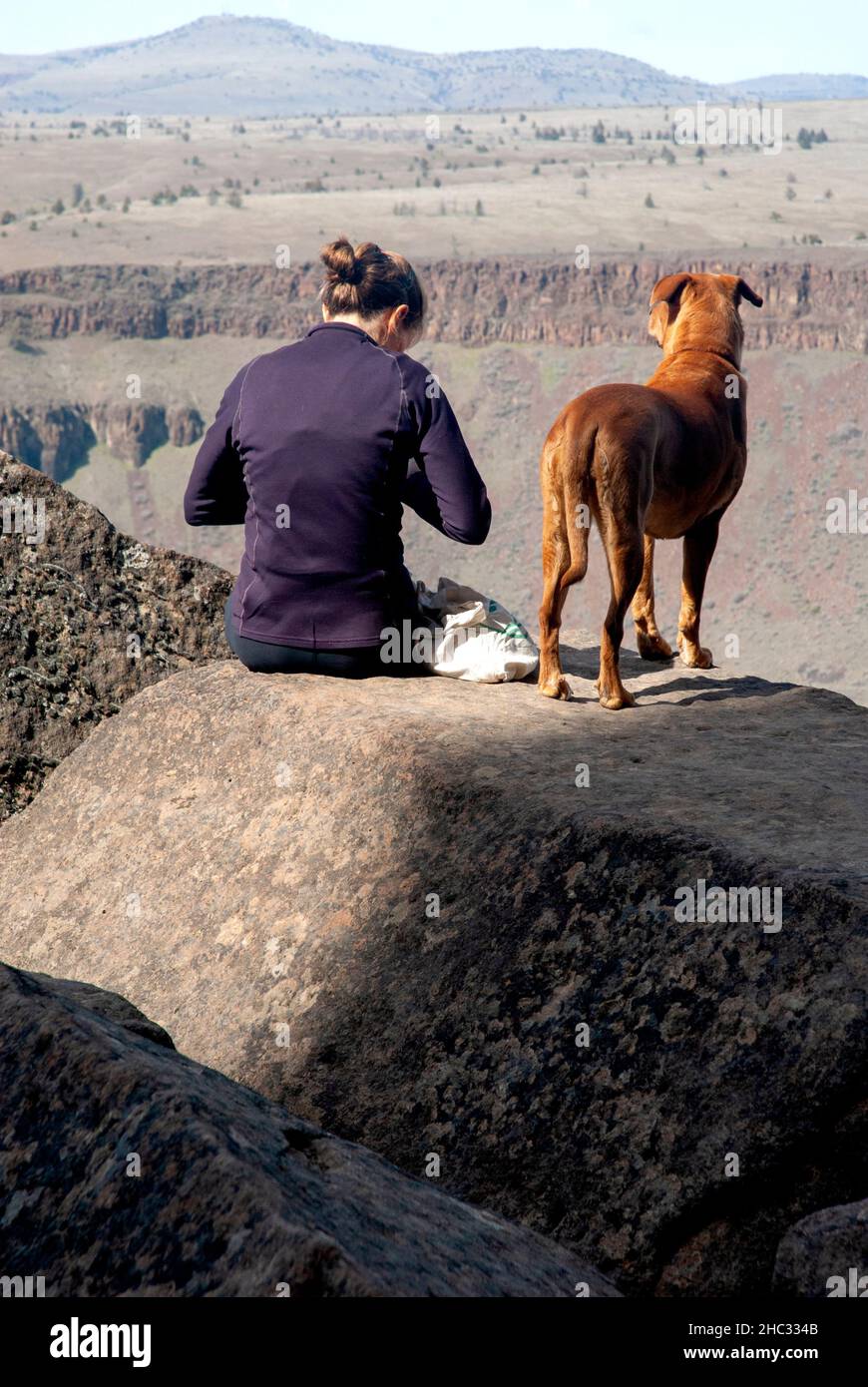 Single woman with dog prepare to rock climb. Trout Creek, Oregon Stock