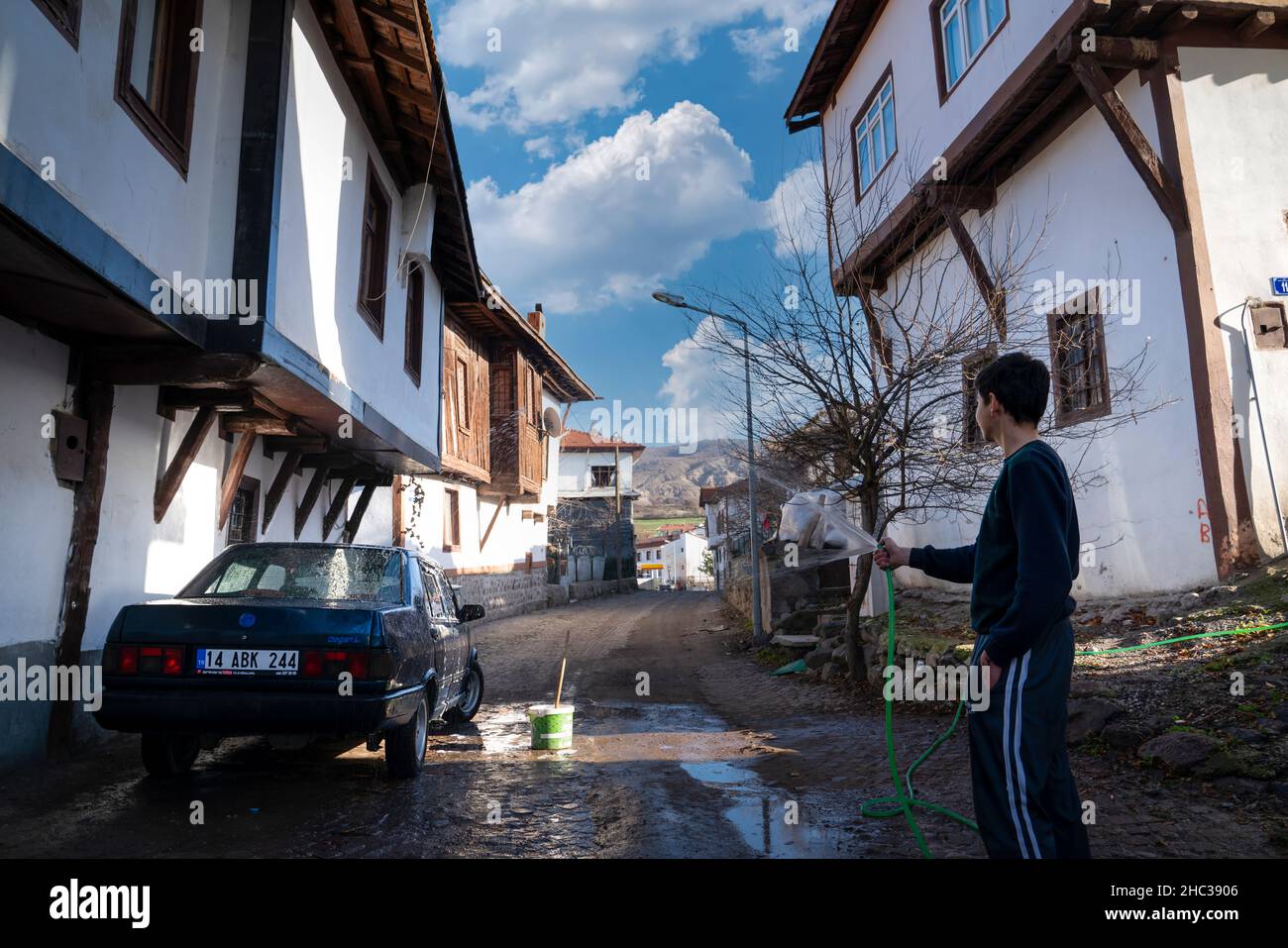 Gudul, Ankara, Turkey - December 12 2021: Man washing his own car with hose on the street. Stock Photo