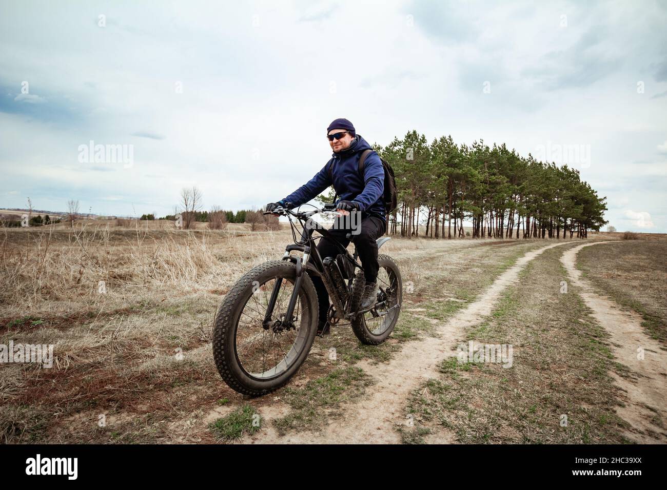 A man rides a fat bike on the road. Rural area. Stock Photo