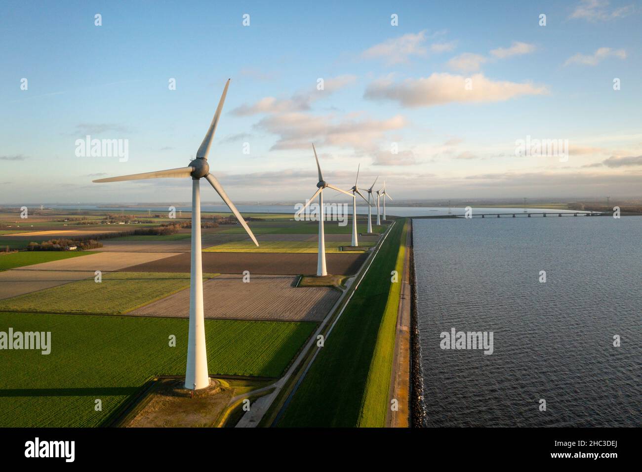 Wind turbines in green fields near lake Stock Photo