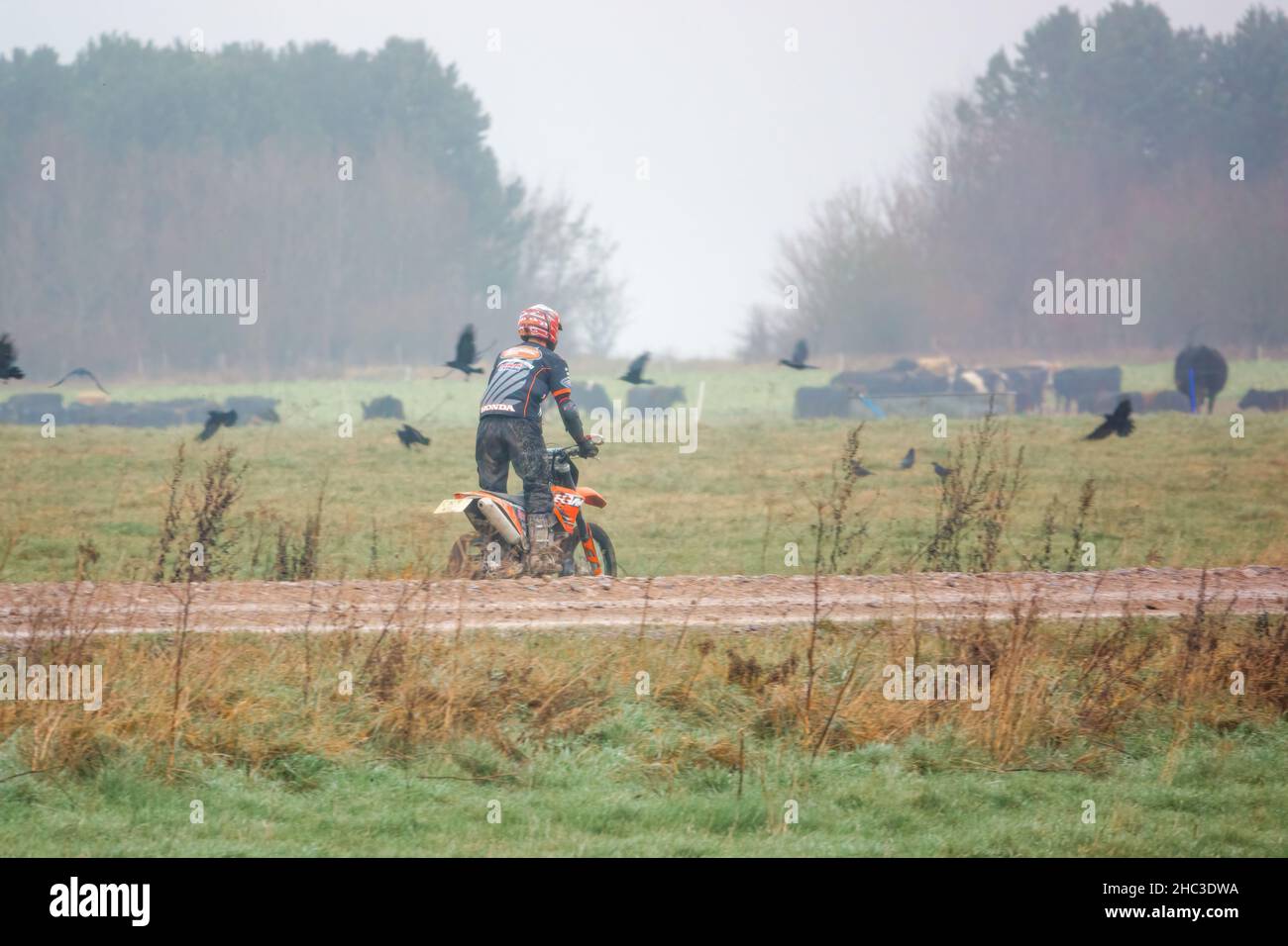a motor cyclist (biker) riding his offroad motorbike along a muddy