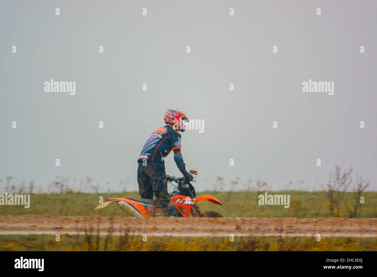 a motor cyclist (biker) riding his offroad motorbike along a muddy