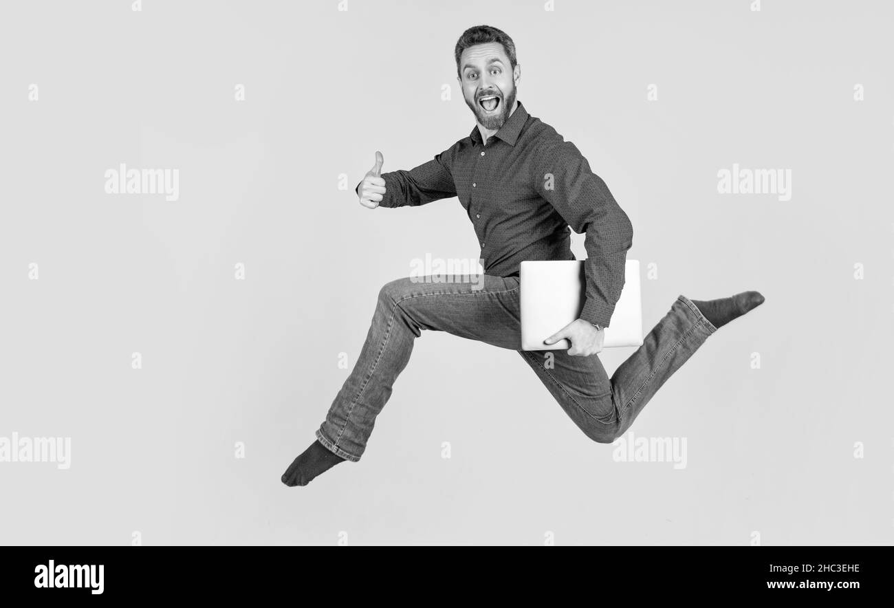 jumping man running while working online on laptop hurry up for shopping show thumb up, success. Stock Photo