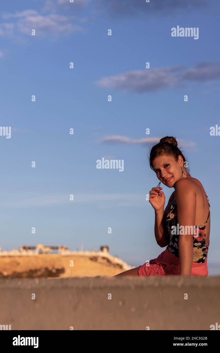Young woman posing and waiting for the sunset sitting in the promenade Stock Photo