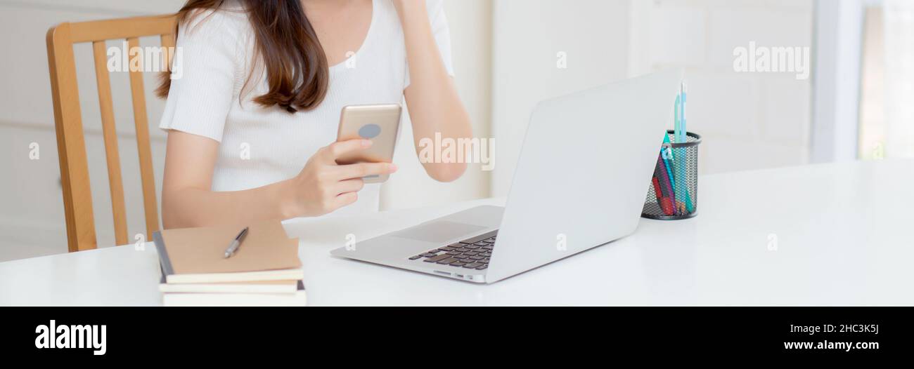 Young asian woman working laptop computer and reading smartphone on ...