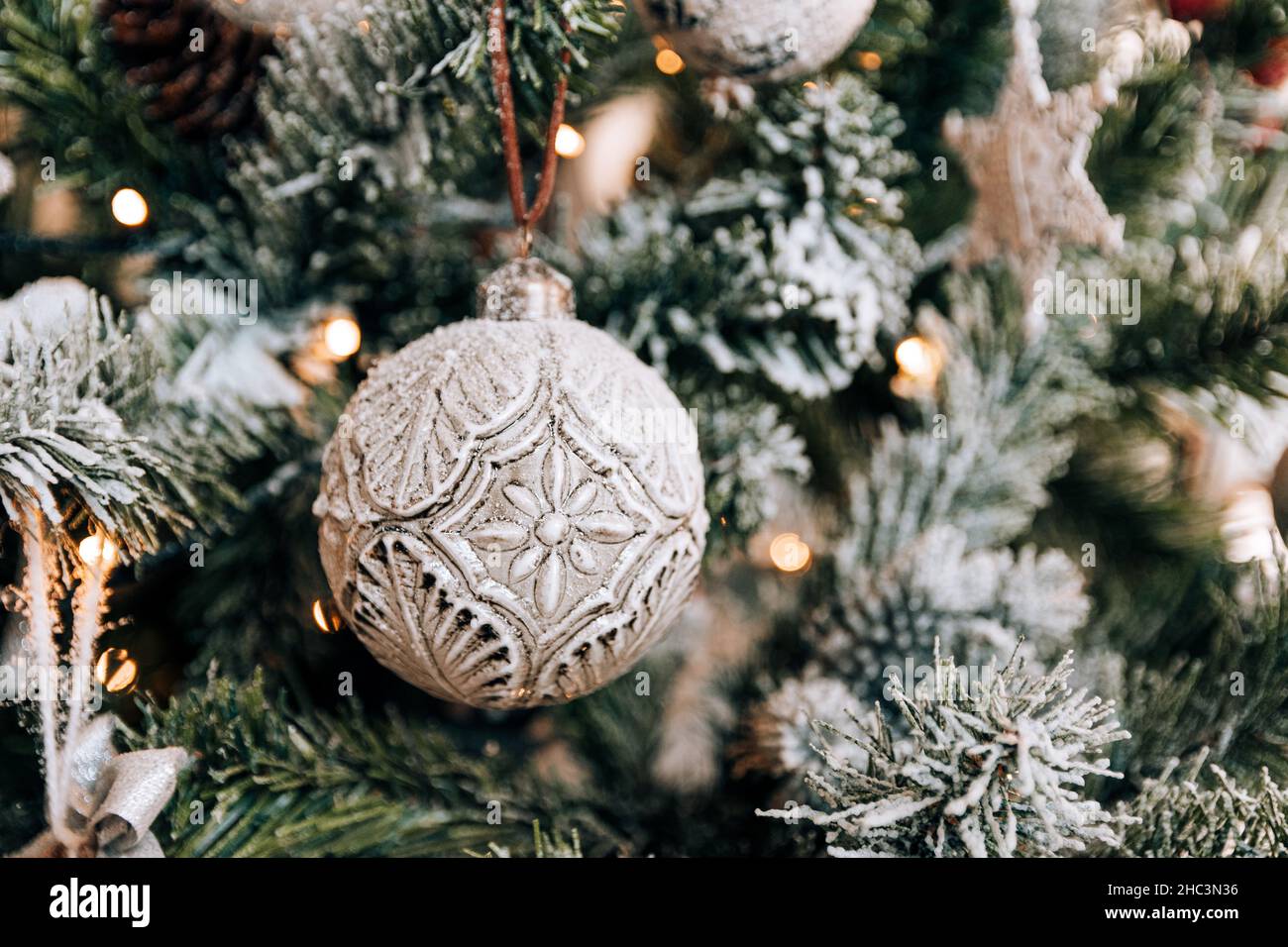 Close-up photo of a silver christmas bauble hanging on a christmas tree ...