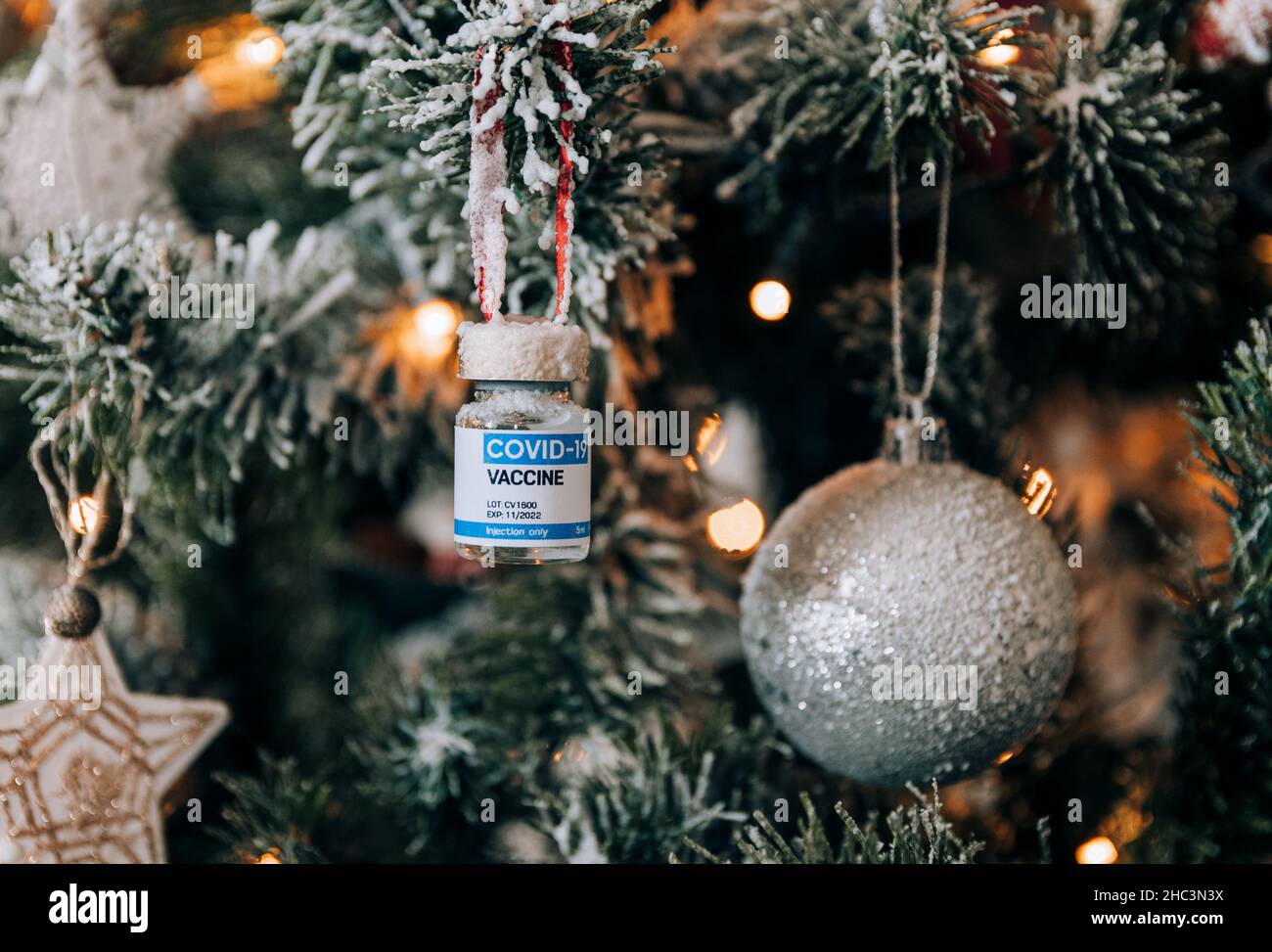 Covid vaccine vial hanging as an ornament on christmas tree Stock Photo