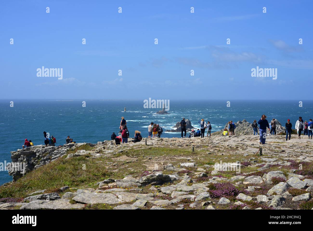 Pointe du Raz, France, 08-07-2021 tourists on the cliffs enjoying the beautiful view on the ocean and the light towers Stock Photo