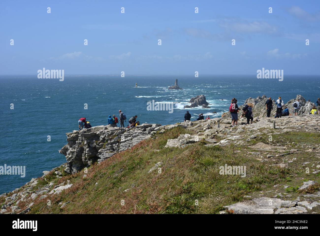 Pointe du Raz, France, 08-07-2021 groups of tourists on the cliffs at the coast watching the light towers Stock Photo