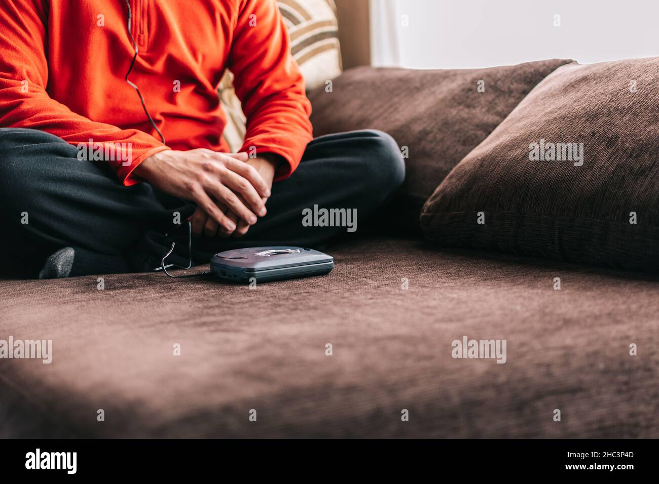 Unrecognizable man with headphones listening to music at home. Relaxed man listening to music on the sofa at home. Stock Photo